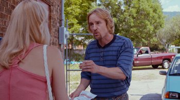 Movie still from “Masterminds” (2015), directed by Jared Hess – A man standing next to a woman in a striped shirt; Medium shot, Over the shoulder angle