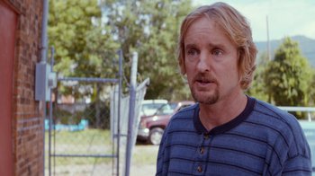 Movie still from “Masterminds” (2015), directed by Jared Hess – A person wearing a blue and black striped shirt; Close Up shot, Over the shoulder angle