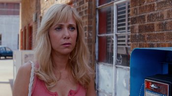 Movie still from “Masterminds” (2015), directed by Jared Hess – A woman standing in front of a brick building; Close Up shot, Over the shoulder angle