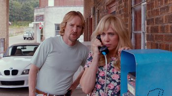 Movie still from “Masterminds” (2015), directed by Jared Hess – A man and a woman standing next to each other on a phone; Medium shot, Over the shoulder angle