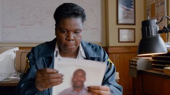 Movie still from “Masterminds” (2015), directed by Jared Hess – A woman looking at a picture of a man; Close Up shot, High angle