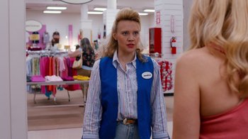 Movie still from “Masterminds” (2015), directed by Jared Hess – A woman in a blue vest is standing in front of a store; Medium shot, Over the shoulder angle