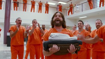 Movie still from “Masterminds” (2015), directed by Jared Hess – A group of men in orange jumpsuits holding towels; Wide shot, Over the shoulder angle