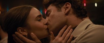 Movie still from “Extremely Wicked, Shockingly Evil and Vile” (2019), directed by Joe Berlinger – A man and a woman kissing each other in front of lights; Close Up shot, Low angle