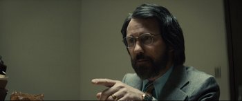 Movie still from “Extremely Wicked, Shockingly Evil and Vile” (2019), directed by Joe Berlinger – A man in a suit and glasses is pointing to the side; Close Up shot, Over the shoulder angle