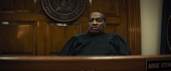 Movie still from “Extremely Wicked, Shockingly Evil and Vile” (2019), directed by Joe Berlinger – A man sitting in a judge's chair in a courtroom; Close Up shot, Low angle