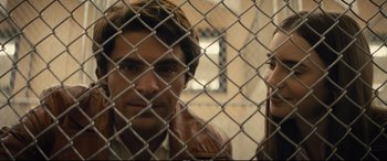 Movie still from “Extremely Wicked, Shockingly Evil and Vile” (2019), directed by Joe Berlinger – A man and a woman standing behind a chain link fence; Close Up shot, Over the shoulder angle