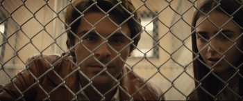 Movie still from “Extremely Wicked, Shockingly Evil and Vile” (2019), directed by Joe Berlinger – A man looking through a chain link fence; Close Up shot, Over the shoulder angle