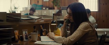 Movie still from “Extremely Wicked, Shockingly Evil and Vile” (2019), directed by Joe Berlinger – A woman sitting at a table drinking a cup of coffee; Medium shot, High angle