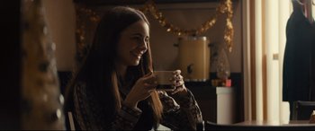 Movie still from “Extremely Wicked, Shockingly Evil and Vile” (2019), directed by Joe Berlinger – A woman is holding a cup of coffee and smiling for the camera; Medium shot, Over the shoulder angle