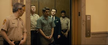 Movie still from “Extremely Wicked, Shockingly Evil and Vile” (2019), directed by Joe Berlinger – A group of men standing next to each other in an elevator; Medium shot, Low angle