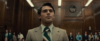 Movie still from “Extremely Wicked, Shockingly Evil and Vile” (2019), directed by Joe Berlinger – A man wearing a suit and tie in a courtroom; Close Up shot, Low angle