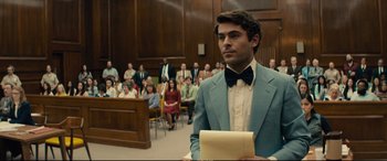 Movie still from “Extremely Wicked, Shockingly Evil and Vile” (2019), directed by Joe Berlinger – A man wearing a suit and bow tie in a court room; Medium shot, Over the shoulder angle