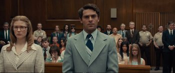 Movie still from “Extremely Wicked, Shockingly Evil and Vile” (2019), directed by Joe Berlinger – A man in a suit and tie standing in front of a group of people; Medium shot, Low angle