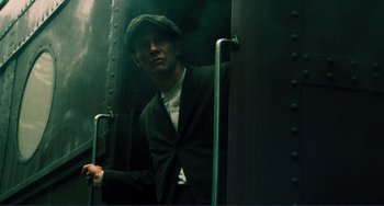 Movie still from “Matewan” (1987), directed by John Sayles – A man in a suit and hat standing on a train; Medium shot, Low angle