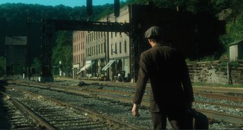 Movie still from “Matewan” (1987), directed by John Sayles – A man walking on train tracks near a train station; Wide shot, High angle