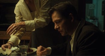 Movie still from “Matewan” (1987), directed by John Sayles – A man sitting at a table with a glass of water; Close Up shot, Over the shoulder angle