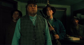 Movie still from “Matewan” (1987), directed by John Sayles – A man holding a rifle in front of another man; Medium shot, Low angle