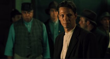 Movie still from “Matewan” (1987), directed by John Sayles – A man standing in front of a group of men; Medium shot, Over the shoulder angle