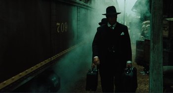 Movie still from “Matewan” (1987), directed by John Sayles – A man in a suit and hat carrying two suitcases; Medium shot, Low angle