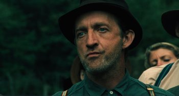 Movie still from “Matewan” (1987), directed by John Sayles – A person wearing a hat with trees in the background; Close Up shot, Low angle