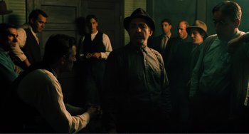 Movie still from “Matewan” (1987), directed by John Sayles – A group of men standing around a man in a hat; Medium shot, Low angle