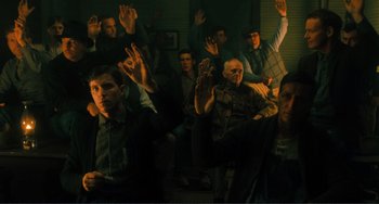 Movie still from “Matewan” (1987), directed by John Sayles – A group of people sitting in a room with their hands raised; Wide shot, High angle