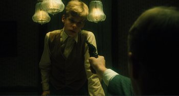 Movie still from “Matewan” (1987), directed by John Sayles – A man holding a gun pointed at a boy in a suit; Close Up shot, Over the shoulder angle