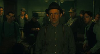 Movie still from “Matewan” (1987), directed by John Sayles – A group of men sitting in a dark room; Medium shot, Low angle