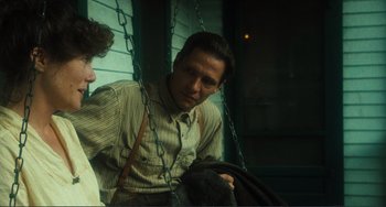 Movie still from “Matewan” (1987), directed by John Sayles – A man sitting on top of a swing next to another man; Medium shot, Over the shoulder angle