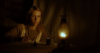 Movie still from “Matewan” (1987), directed by John Sayles – A woman sitting in front of a lit lamp; Medium shot, Low angle