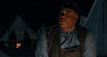 Movie still from “Matewan” (1987), directed by John Sayles – A man wearing a hat and a vest looking to his left; Close Up shot, Over the shoulder angle