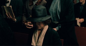 Movie still from “Matewan” (1987), directed by John Sayles – A woman wearing a black hat sitting next to two other people; Medium shot, High angle