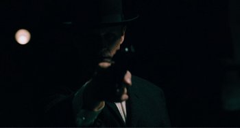 Movie still from “Matewan” (1987), directed by John Sayles – A man in a suit and a hat holding a gun; Close Up shot, Over the shoulder angle
