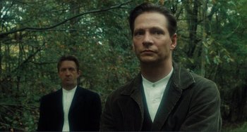 Movie still from “Matewan” (1987), directed by John Sayles – Two men standing next to each other near a forest; Medium shot, Low angle