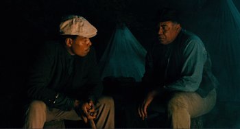 Movie still from “Matewan” (1987), directed by John Sayles – Two men are sitting in a dark room; Medium shot, Over the shoulder angle