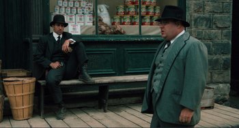 Movie still from “Matewan” (1987), directed by John Sayles – Two men sitting on a bench in front of a store; Wide shot, Low angle