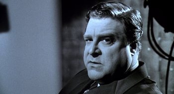 Movie still from “Matinee” (1993), directed by Joe Dante – A man in a suit and tie looking to his left; Close Up shot, Low angle