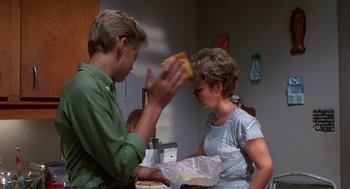 Movie still from “Matinee” (1993), directed by Joe Dante – A man and a woman sitting at a dinner table; Medium shot, Over the shoulder angle