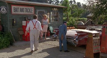 Movie still from “Matinee” (1993), directed by Joe Dante – A couple of people standing next to a red car; Wide shot, High angle