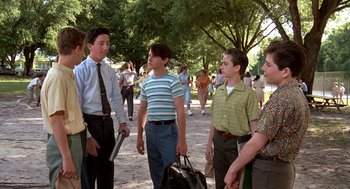 Movie still from “Matinee” (1993), directed by Joe Dante – A group of young men standing next to each other on a sidewalk; Medium shot, Over the shoulder angle
