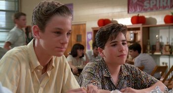 Movie still from “Matinee” (1993), directed by Joe Dante – Two young men sitting at a table in front of a group of people; Medium shot, Low angle