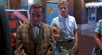 Movie still from “Matinee” (1993), directed by Joe Dante – A man and two young boys standing next to each other; Medium shot, Low angle