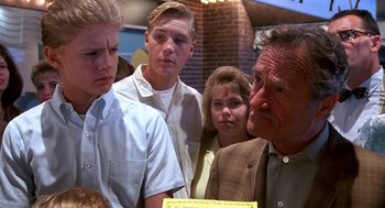 Movie still from “Matinee” (1993), directed by Joe Dante – An older man and three young men standing next to each other in front of a brick wall; Medium shot, Over the shoulder angle