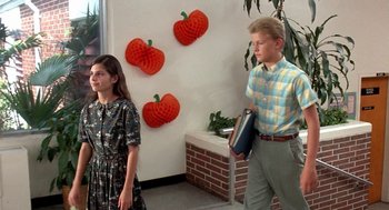 Movie still from “Matinee” (1993), directed by Joe Dante – A man and a woman are standing in front of a wall; Medium shot, High angle