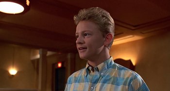 Movie still from “Matinee” (1993), directed by Joe Dante – A young man with blonde hair and a blue and yellow plaid shirt; Close Up shot, Low angle