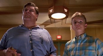 Movie still from “Matinee” (1993), directed by Joe Dante – Two men standing next to each other in front of a ceiling light; Medium shot, Low angle