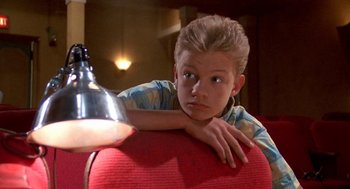 Movie still from “Matinee” (1993), directed by Joe Dante – A young boy leaning on a red couch; Close Up shot, High angle