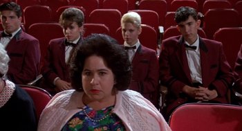 Movie still from “Matinee” (1993), directed by Joe Dante – A group of people sitting in a room with red seats; Medium shot, Over the shoulder angle