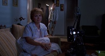 Movie still from “Matinee” (1993), directed by Joe Dante – A woman sitting on a chair in front of a movie projector; Wide shot, Low angle